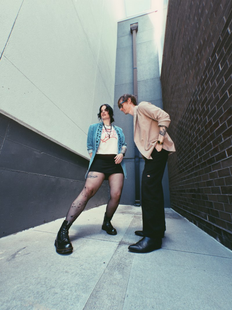 Two people posing in a narrow alley during a photoshoot for Hum